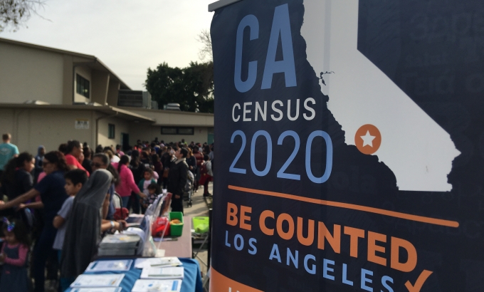 2020 Census banner with people in the background at an outreach event.
